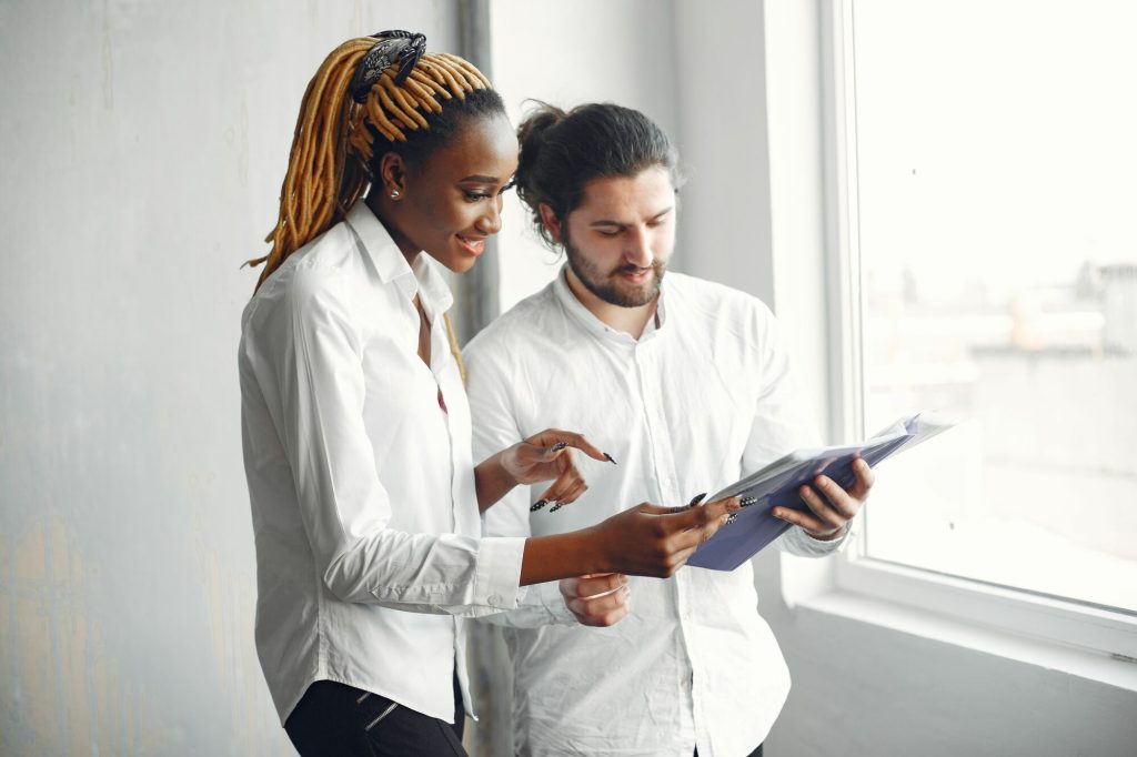 Deux collègues consultent ensemble une tablette et échangent en souriant.